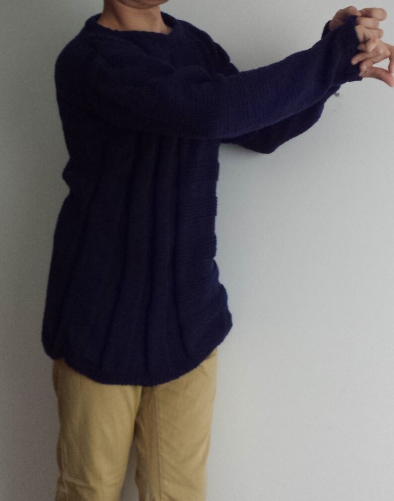 May include: A dark blue knitted sweater with long sleeves and a round neckline.