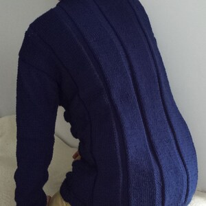 May include: A dark blue knitted sweater with vertical ribbed detailing. The sweater has long sleeves and a crew neck.