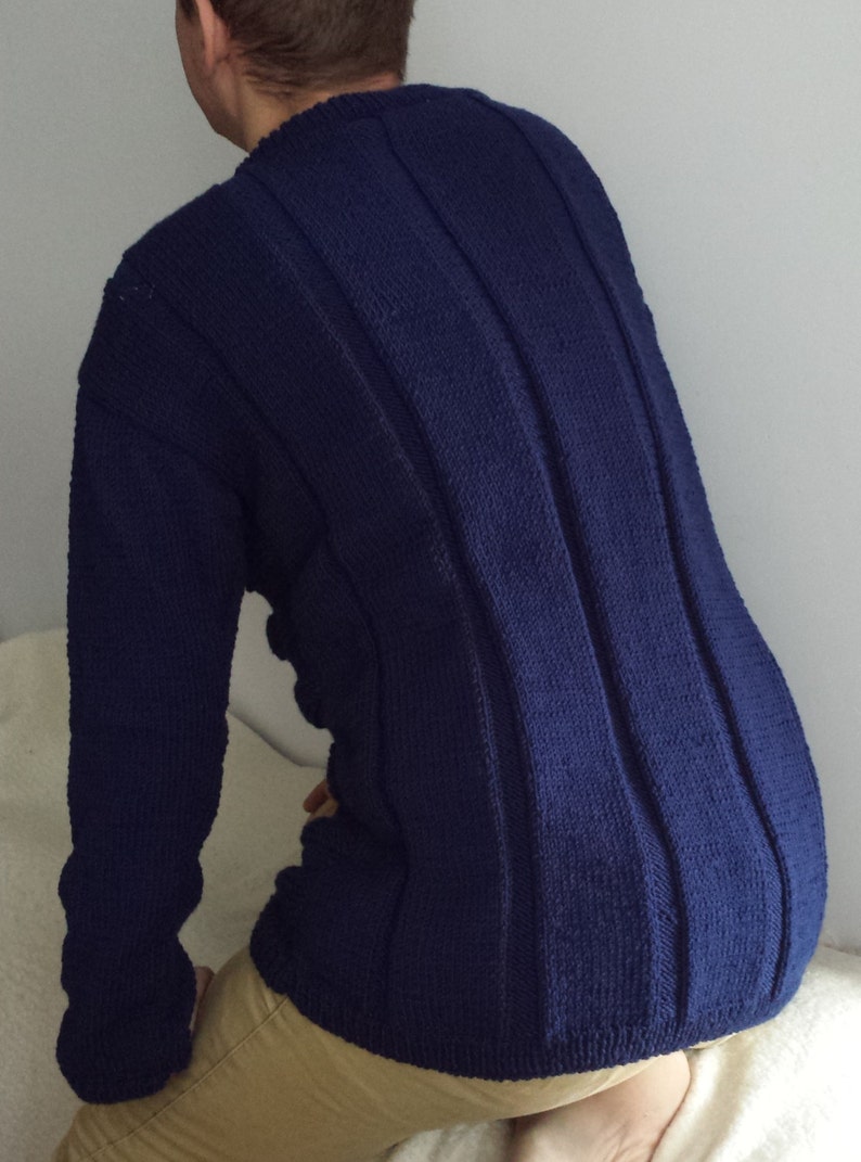 May include: A dark blue knitted sweater with vertical ribbed detailing. The sweater has long sleeves and a crew neck.