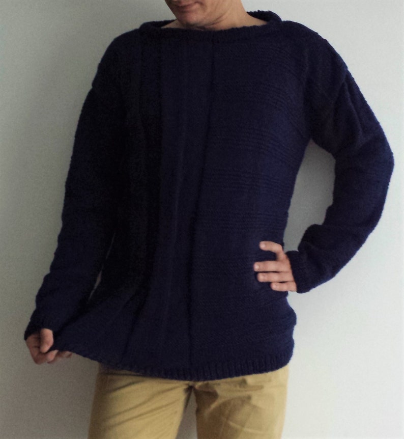 May include: A dark blue knitted sweater with long sleeves and a round neckline.