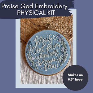 May include: A blue embroidery hoop with the text "Praise God from whom all blessings flow" embroidered in white thread. The hoop is surrounded by a floral design in shades of blue and white. The hoop is 8.5 inches in diameter.