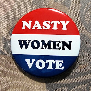 May include: A red, white, and blue button with the text "Nasty Women Vote" in white letters.