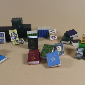 May include: A collection of miniature books with various titles and covers, including "The Tempest", "Federal Law", "The First Christmas", "John Grisham Client", "Jolly Alphabets", "Little Red Hen", "Shakespeare", "The Bridge", and "An Endless Night".
