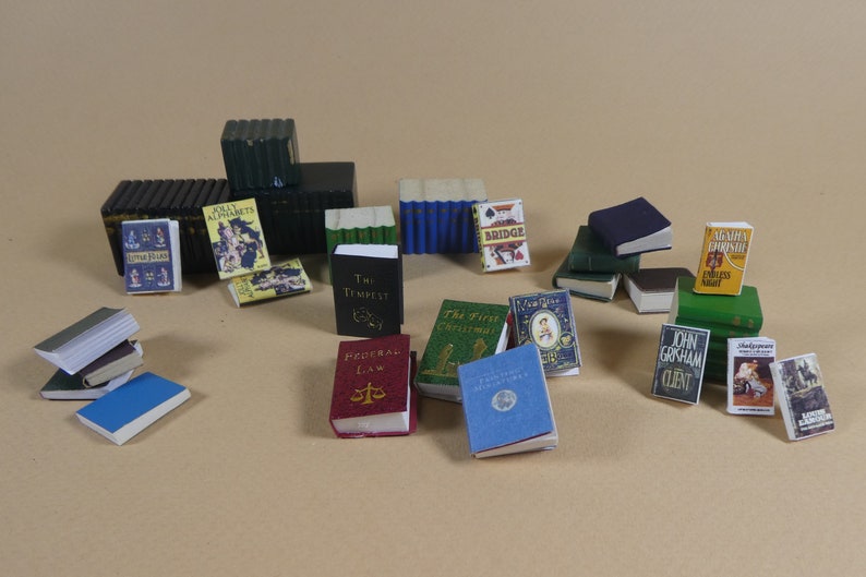 May include: A collection of miniature books with various titles and covers, including "The Tempest", "Federal Law", "The First Christmas", "John Grisham Client", "Jolly Alphabets", "Little Red Hen", "Shakespeare", "The Bridge", and "An Endless Night".