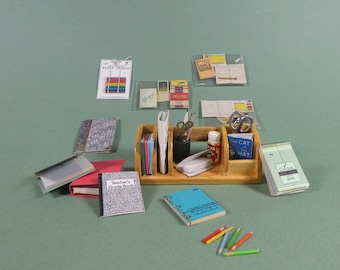 May include: A wooden desk organizer with various school supplies, including notebooks, pencils, and a teacher's grade book. The organizer has five compartments and is filled with colorful items.