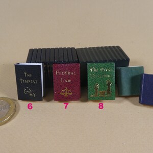 May include: A collection of miniature books with different colored covers. The books are titled "The Tempest", "Federal Law", "The First Christmas", and an unreadable title. The books are arranged in a row on a light brown surface.