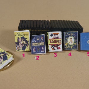 May include: Five miniature books with colorful covers. The books are titled "A Jolly Alphabets", "Little Folks", "Bridge", "Mrs. Pig's Green Gown", and "Painting Miniature", respectively.
