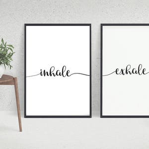 Peut inclure: Deux impressions encadrées noires avec des fonds blancs et une calligraphie noire. L'impression de gauche dit "inhale" et l'impression de droite dit "exhale".