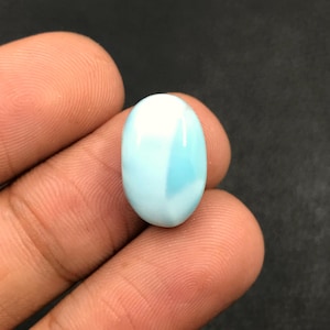 Pode incluir: Uma gema oval de cabochão azul claro com redemoinhos brancos e azuis.