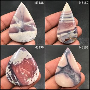 Puede incluir: Cuatro piedras preciosas pulidas en forma de lágrima, cada una con patrones y colores únicos. Las piedras presentan tonos de púrpura, crema y marrón, con vetas y veteados visibles. Cada piedra está etiquetada con un identificador de texto blanco: M3188, M3189, M3190 y M3191.