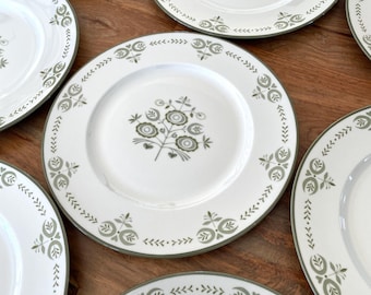 May include: Set of six white ceramic dinner plates with a green floral design and a green border. The plates have a simple, elegant design.