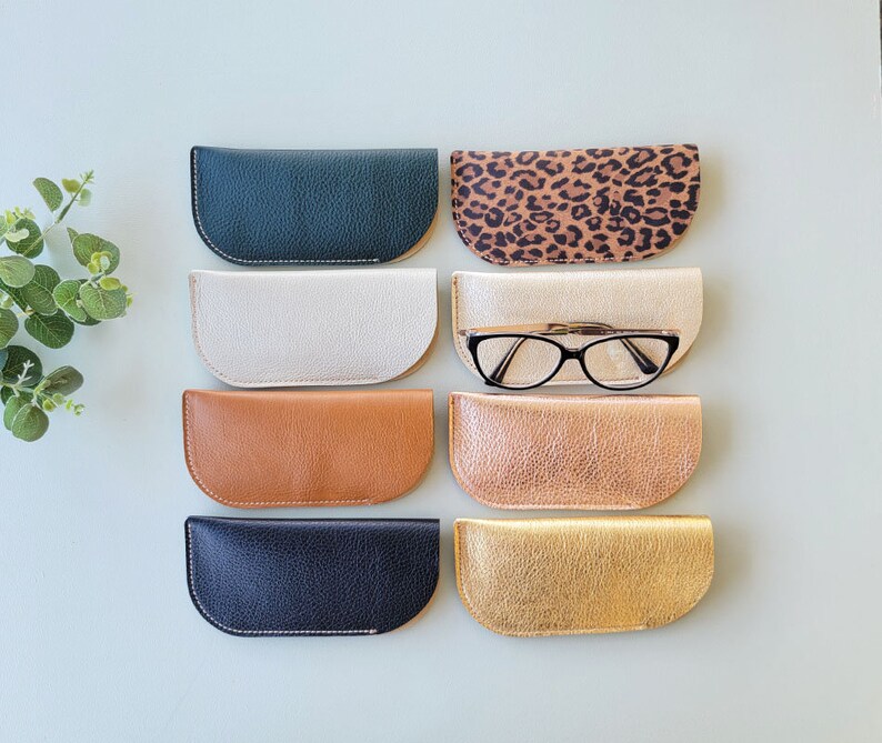 May include: Eight different colored leather eyeglass cases. The cases are all half-moon shaped and have a stitched edge. One case has a leopard print pattern.