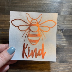 May include: A copper-colored vinyl decal with a bee silhouette and the word "kind" in a cursive font.