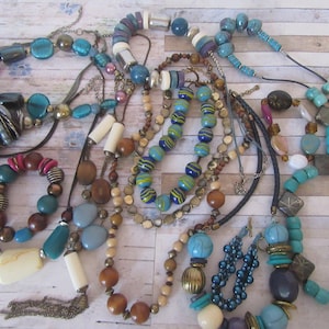 Peut inclure: Un ensemble de colliers et de bracelets en perles colorées dans des tons de bleu, marron, turquoise et blanc. Les colliers sont faits de divers matériaux, notamment du bois, du verre et du métal.