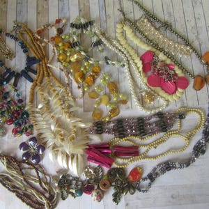 May include: A collection of various necklaces in different styles and colors. Includes beaded, pearl, and pendant necklaces. Some necklaces feature colorful beads, while others have shell or stone accents. A diverse selection of jewelry.