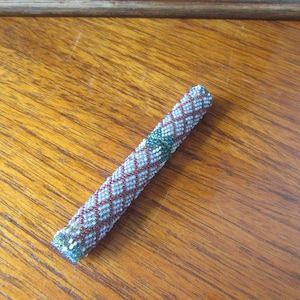 May include: A beaded pen holder with a white, blue, and red geometric pattern.