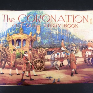 Op de afbeelding: Vintage "The Coronation Cut-Out Story Book" met een kleurrijke illustratie van een koninklijke processie. De omslag toont een gouden koets, paarden en figuren in historische kleding. Uitgegeven door Dean.