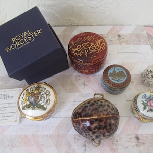 以下が含まれることがあります： 小さな装飾箱のコレクション。箱は磁器製で、紋章、花柄、貝殻など、さまざまなデザインが施されています。箱はすべて色とサイズが異なります。