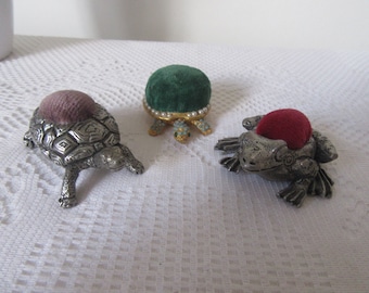 Vintage pewter and gold tone metal pin cushions.Tortoise and frog pewter red&purple felt.. Turtle faux pearls gold toned green felt.