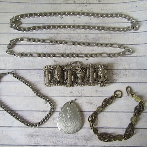 Peut inclure: Divers bijoux vintage, dont deux colliers à chaîne argentés, un bracelet détaillé avec des figurines, un bracelet à chaîne avec un fermoir, un pendentif et un bracelet doré.