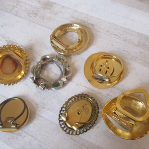 May include: Seven gold-toned metal belt buckles with various designs. Some buckles have a decorative, ornate design, while others are more simple. The buckles are all in good condition and would be a great addition to any belt collection.