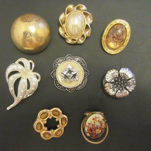Peut inclure: Assortiment de huit broches décoratives de styles et de couleurs variés. Les broches présentent des motifs floraux, géométriques et abstraits. Certaines broches ont une finition dorée, tandis que d'autres ont une finition argentée.