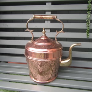 1800年代のビクトリア朝様式の銅と真鍮製の大型ケトル。装飾的な暖炉用ケトル。銅の彫刻が施された本体、真鍮製の注ぎ口、ハンドル、蓋のノブ。
