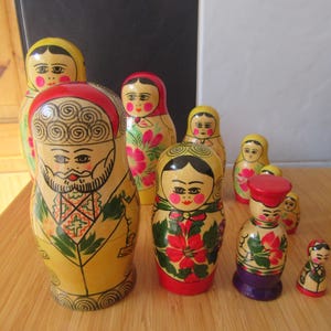 Könnte beinhalten: Eine Sammlung handbemalter russischer Matrjoschka-Puppen in verschiedenen Größen. Die Puppen weisen detaillierte Gesichter, florale Muster und traditionelle Kleidung in verschiedenen Farben wie Rot, Gelb, Grün und Lila auf.