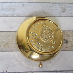 Vintage Estee Lauder Sagittarius Lucidity compact. Gold-tone with crystals. Translucent pressed powder. Pre-loved in good condition.