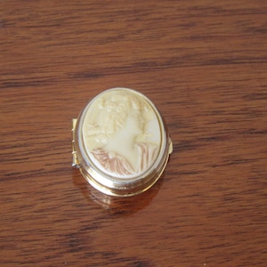 Cameo pill box. Gold-tone, enamel look lined, plastic faux cameo pill box.