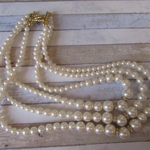 Vintage Signed Monet pearls and crystals necklace. 3 Strands of Creamy pearlescent faux pearls. Gold-tone & crystals spacers. Like new.