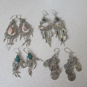 Può includere: Cinque paia di orecchini d'argento con diversi design. Due paia presentano pietre rosa e verdi, mentre gli altri tre paia hanno pietre verdi. Gli orecchini sono tutti d'argento e hanno un design delicato e intricato.