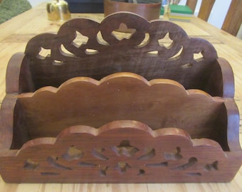 May include: A wooden letter holder with two compartments. The holder has a decorative carved design on the front and top.