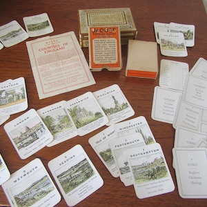 Könnte beinhalten: Ein antikes Jaques-Spielset mit Karten, die englische Grafschaften zeigen, einem Regelblatt und einer dekorativen Box. Die Karten zeigen Orte wie London, Exeter und Weymouth.