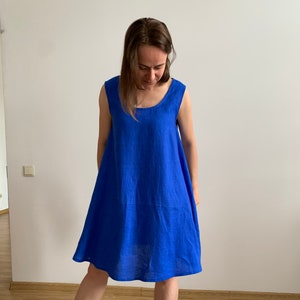 Puede incluir: Un vestido de lino azul real sin mangas, hasta la rodilla, con cuello redondo.