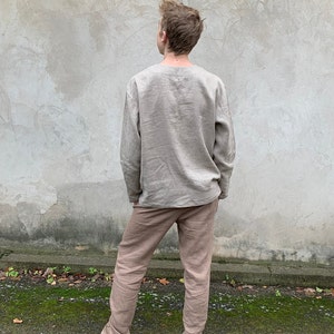 May include: A person wearing a light brown linen shirt and matching pants. The shirt has long sleeves and a relaxed fit. The pants are straight-leg and have a casual look.