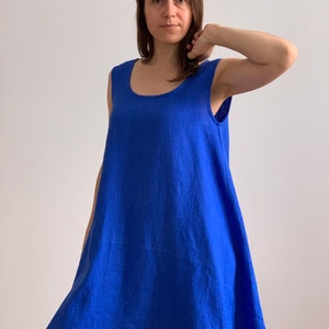 Puede incluir: Un vestido de lino azul real sin mangas, con cuello redondo y un corte holgado y fluido.