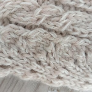 Puede incluir: Primer plano de una tela de punto beige con un patr&oacute;n de punto de cable.