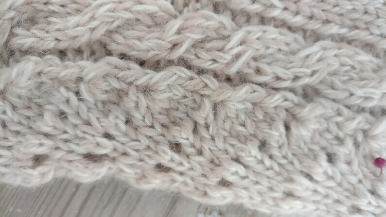 Puede incluir: Primer plano de una tela de punto beige con un patr&oacute;n de punto de cable.