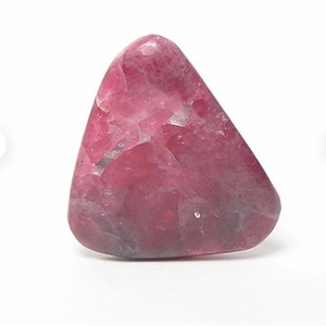Peut inclure: Une pierre précieuse rose en forme de triangle avec une surface rugueuse et texturée.