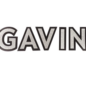 May include: The name "GAVIN" is spelled out in silver glitter letters with black outlines.