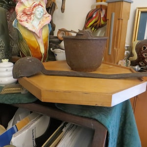 May include: A wooden octagonal tray with a brown metal ladle, a rusty cast iron pot, and a white ceramic beehive-shaped jar on top.