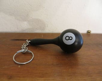 May include: Black and white 8 ball keychain with a silver chain. The 8 ball is made of wood and has a black and white design.