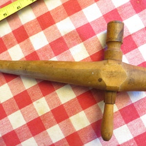 May include: A wooden beer tap with a long, slender spout and a handle on the side. The tap is made of light brown wood and has a natural finish.