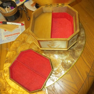 May include: A wooden jewellery box with a red velvet interior. The box has a hinged lid and is decorated with a floral design. The box is open and the interior is visible.
