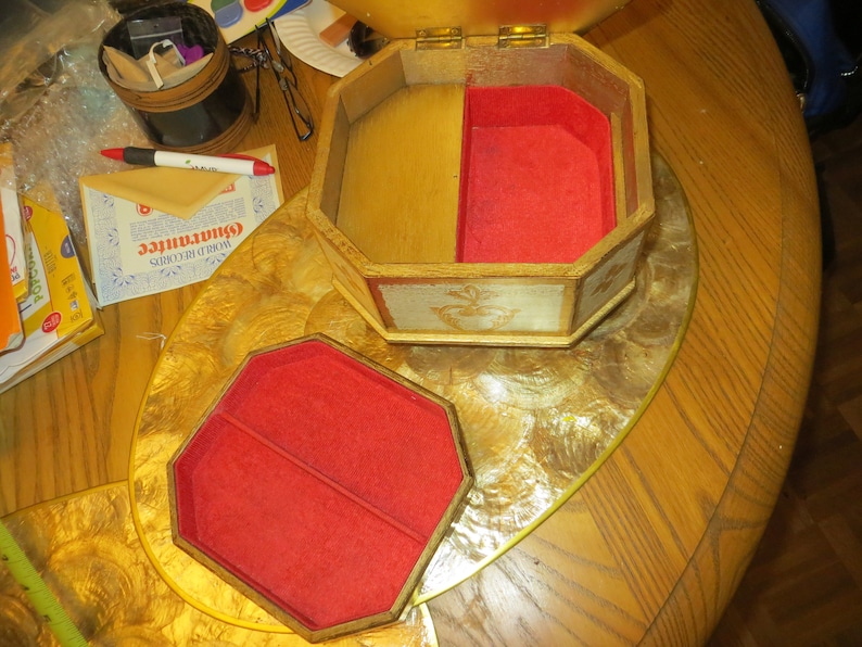 May include: A wooden jewellery box with a red velvet interior. The box has a hinged lid and is decorated with a floral design. The box is open and the interior is visible.