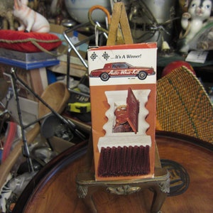May include: A rectangular cardboard box for an Auto-Whis-Kit featuring a graphic of a vintage car and the text "...It's A Winner!" and "Auto-Whis-Kit". The box displays a white plastic brush with a maroon bristle head and a small hinged compartment.