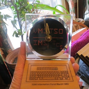 May include: A wooden plaque with a black and red clock face that reads "VMTSO IMS TCS" and a keyboard outline with the text "3290 Information Panel March 1983".
