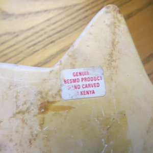 May include: A white star-shaped carved stone sculpture with a label that reads "GENUINE BESMO PRODUCT HAND CARVED IN KENYA".