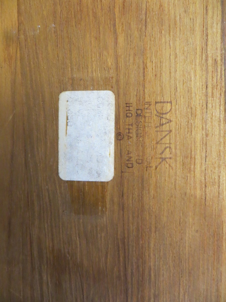 May include: A close-up of a wooden surface with a white label and the text "DANSK  DESIGN  IN  DENMARK  IHQ  THA  (C)"